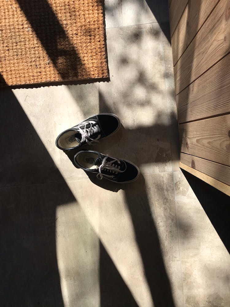 Stylish Sneakers On Floor Near Rug At Home