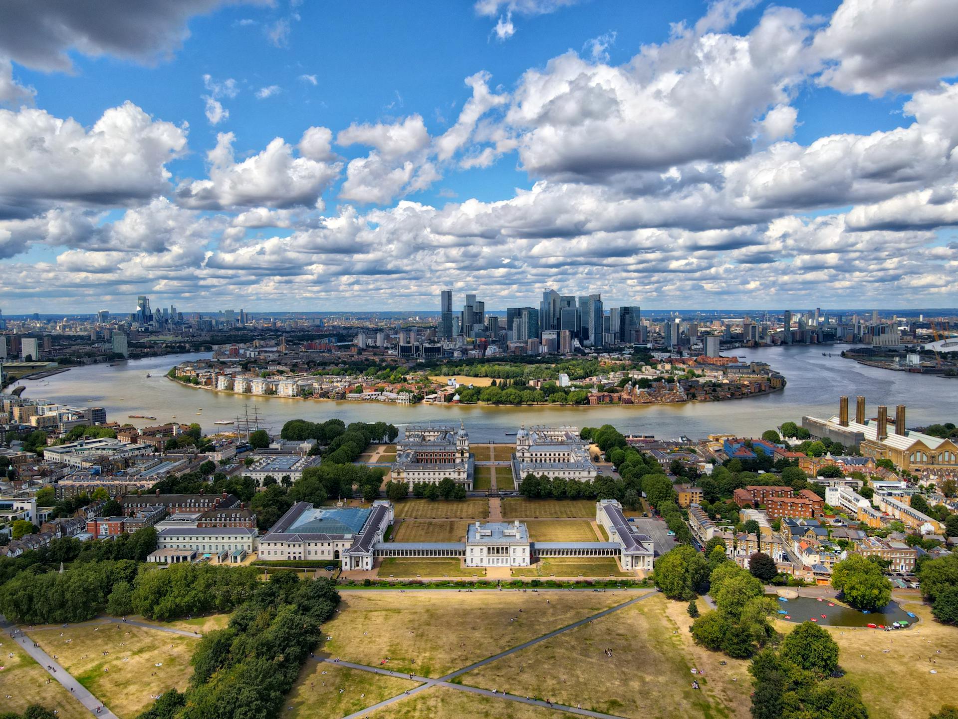 Stunning aerial shot of Greenwich with London's skyline in the background under a dramatic sky.