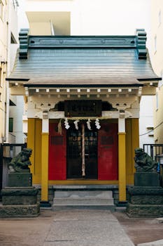 Historic Japanese shrine entrance in Tokyo with decorative statues and vibrant red door.