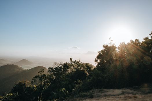 Breathtaking view of mountains and forest with sunlight streaming through trees.
