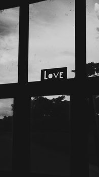 Silhouette of a window with a 'Love' sign in grayscale, evoking simplicity.