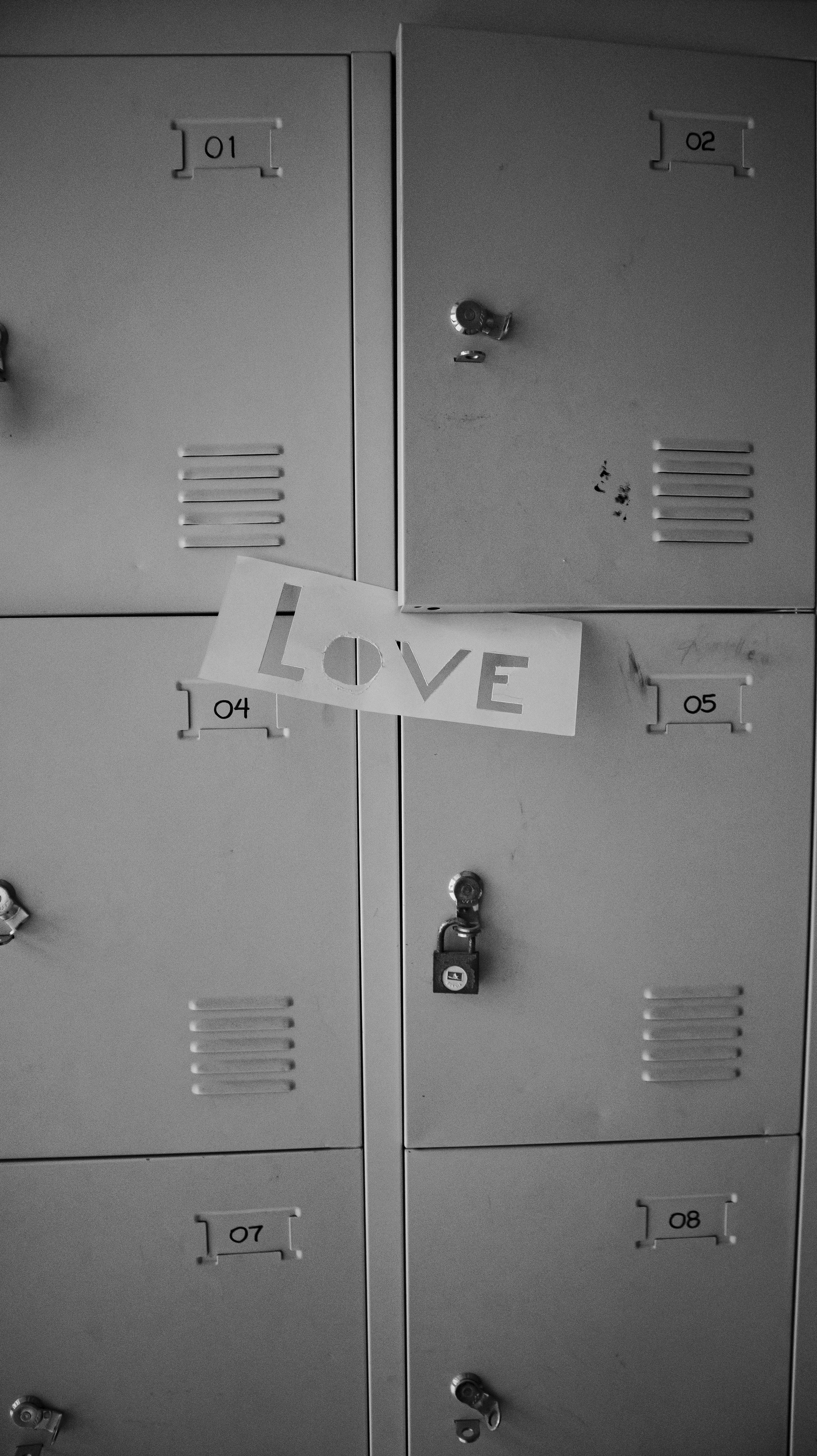 Paper with LOVE message taped on white lockers in black and white exposure.
