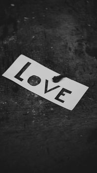 Grayscale minimalist photo with the word 'Love' on paper, featuring a dramatic tone.
