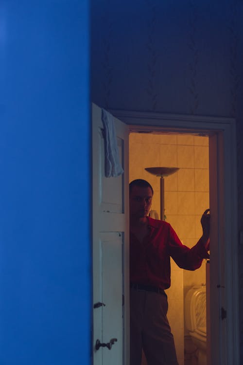 Free Man in Red Dress Shirt and Black Pants Standing on Doorway Stock Photo