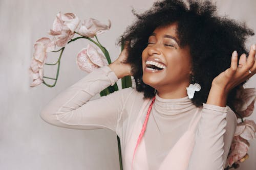 Woman in White Long Sleeve Shirt Holding White Flower