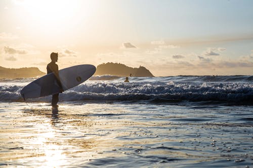 Unrecognizable man standing with surfboard on beach