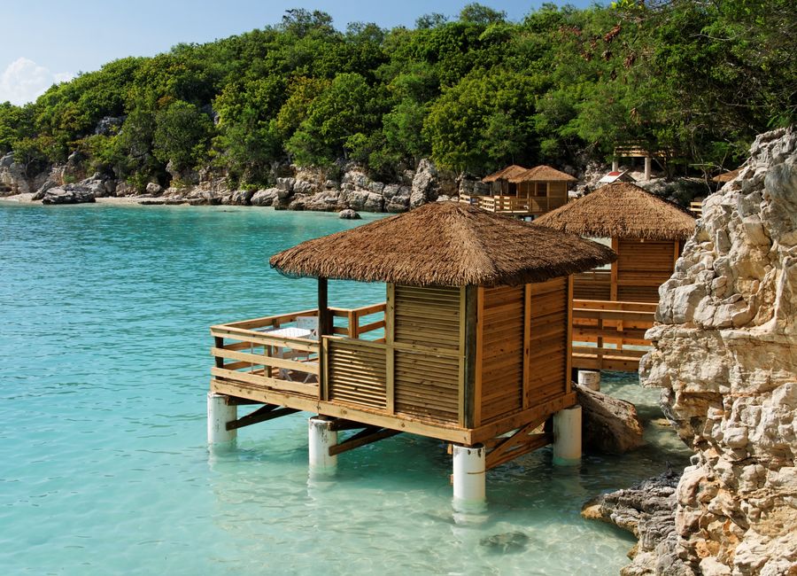 Scenic view of thatched huts on stilts over turquoise waters along the Haitian coast.
