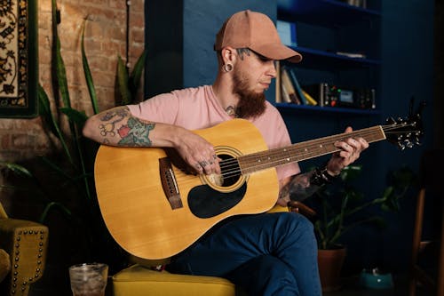 Man With Tattoos Playing an Acoustic Guitar