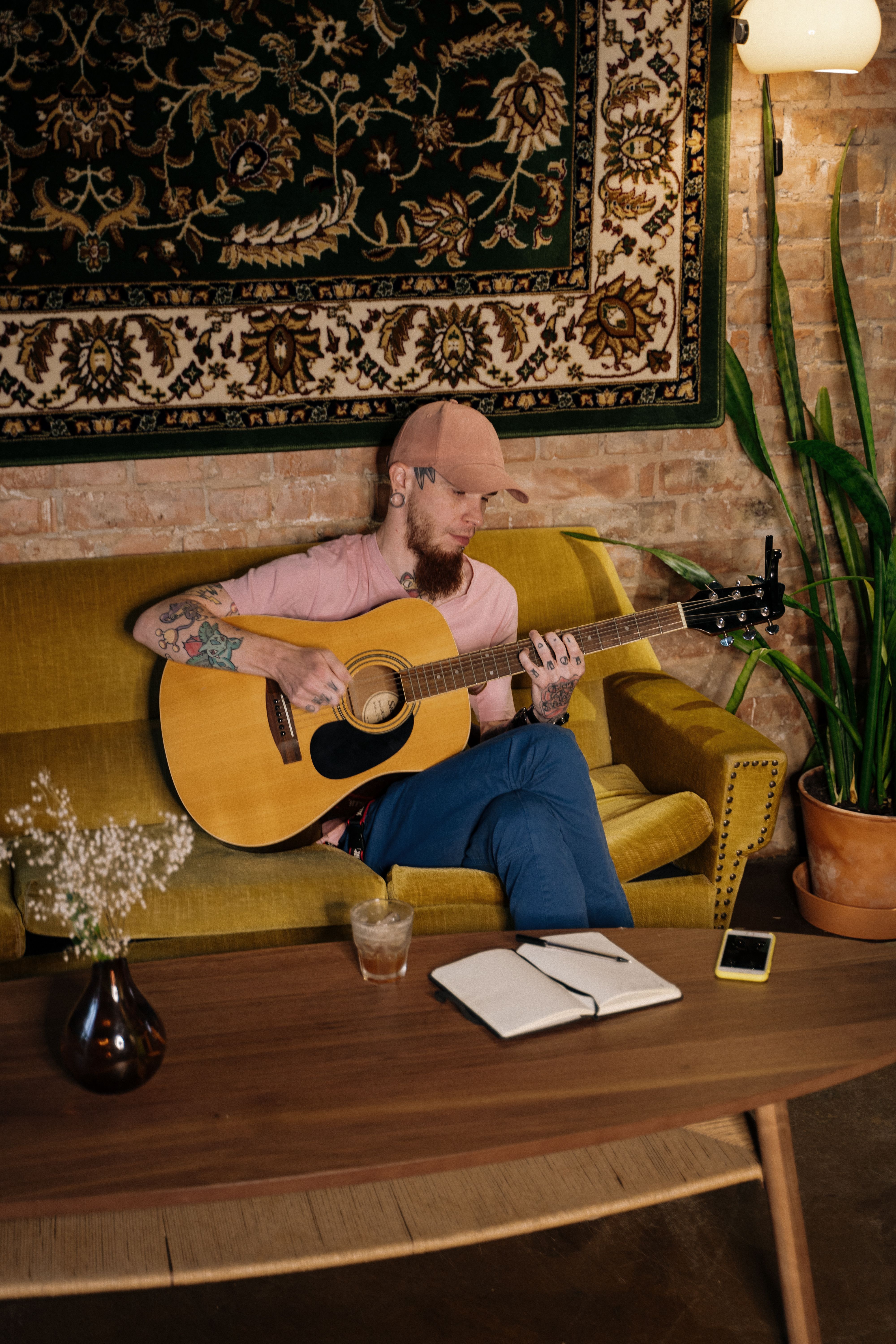 A Man Sitting on the Sofa Playing Guitar · Free Stock Photo