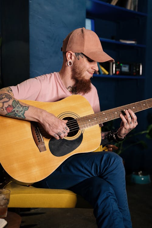 Man With Tattoos Playing an Acoustic Guitar