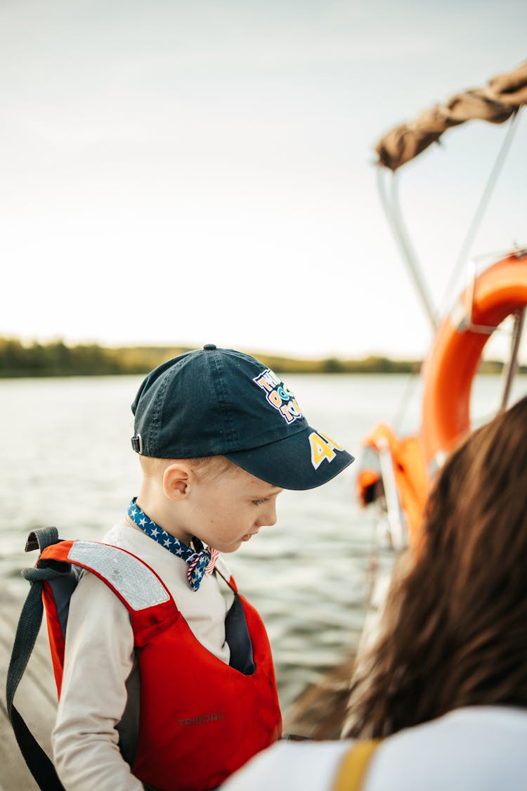 A Young Boy Wearing A Cap And Life Vest