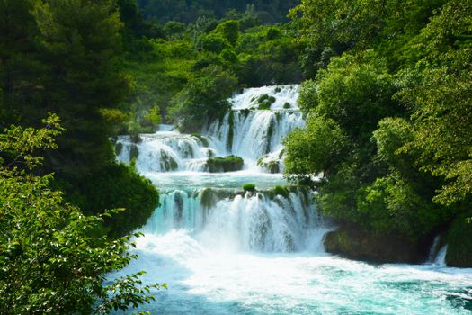 Captivating waterfall cascade in a vibrant green forest, perfect travel destination.