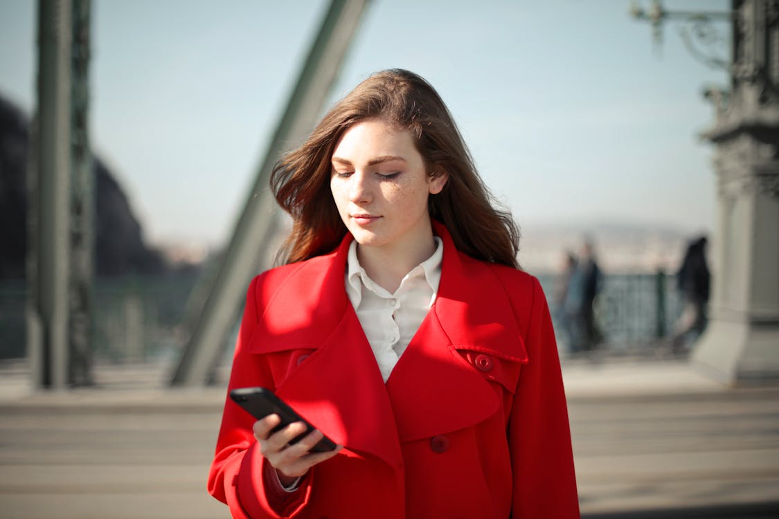 A Woman in Red Coat Using Her Mobile Phone