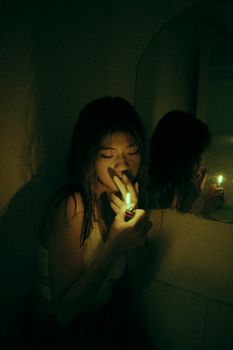 这是一张黑暗而大气的图像，画面中一名女子在光线昏暗的空间里用打火机点燃香烟