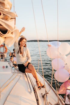 一位微笑的女人在游艇上与朋友和气球一起庆祝日落之旅