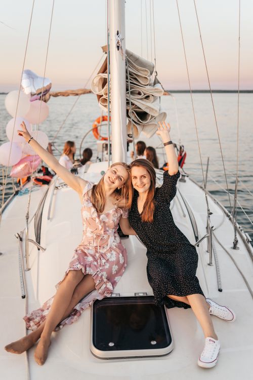 Free Two women enjoying a sunset party on a yacht, celebrating with friends and balloons. Stock Photo