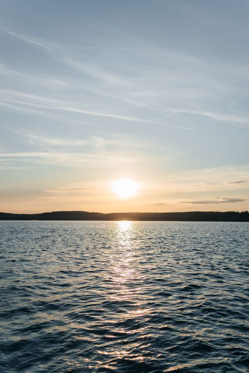 Free A serene sunset over calm lake waters, ideal for nature backgrounds. Stock Photo