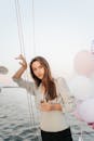 一名女子在装有气球的游艇上拿着香槟杯，在海上享受着一个宁静的夜晚