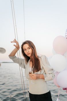 一名女子在海上，乘着装有气球的游艇，手持香槟杯，享受着一个宁静的夜晚