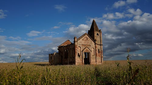 Exterior of ruined medieval church with remaining masonry walls and crosses on top located on spacious grassy valley