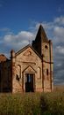 Exterior of destroyed ancient Catholic church with remaining grunge brick walls forgotten on green spacious meadow in countryside