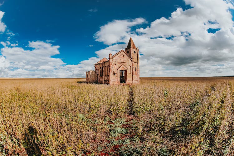 Shabby Stone Church In Rural Field In Sunlight