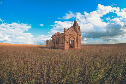 Exterior of old stone christian church with shabby walls located in field against cloudy blue sky in Brazil