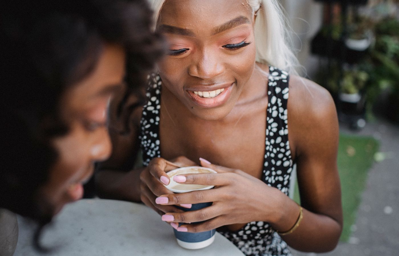 Two women enjoying a coffee and conversation outdoors, capturing a moment of leisure and friendship.