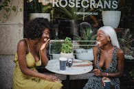 两个朋友在咖啡馆里喝着咖啡，分享欢笑，营造出一片欢乐的户外场景