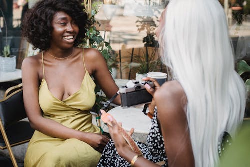 Woman Holding a Camera While Talking to Another Woman