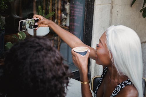 Woman Holding a Paper Cup While Taking a Selfie