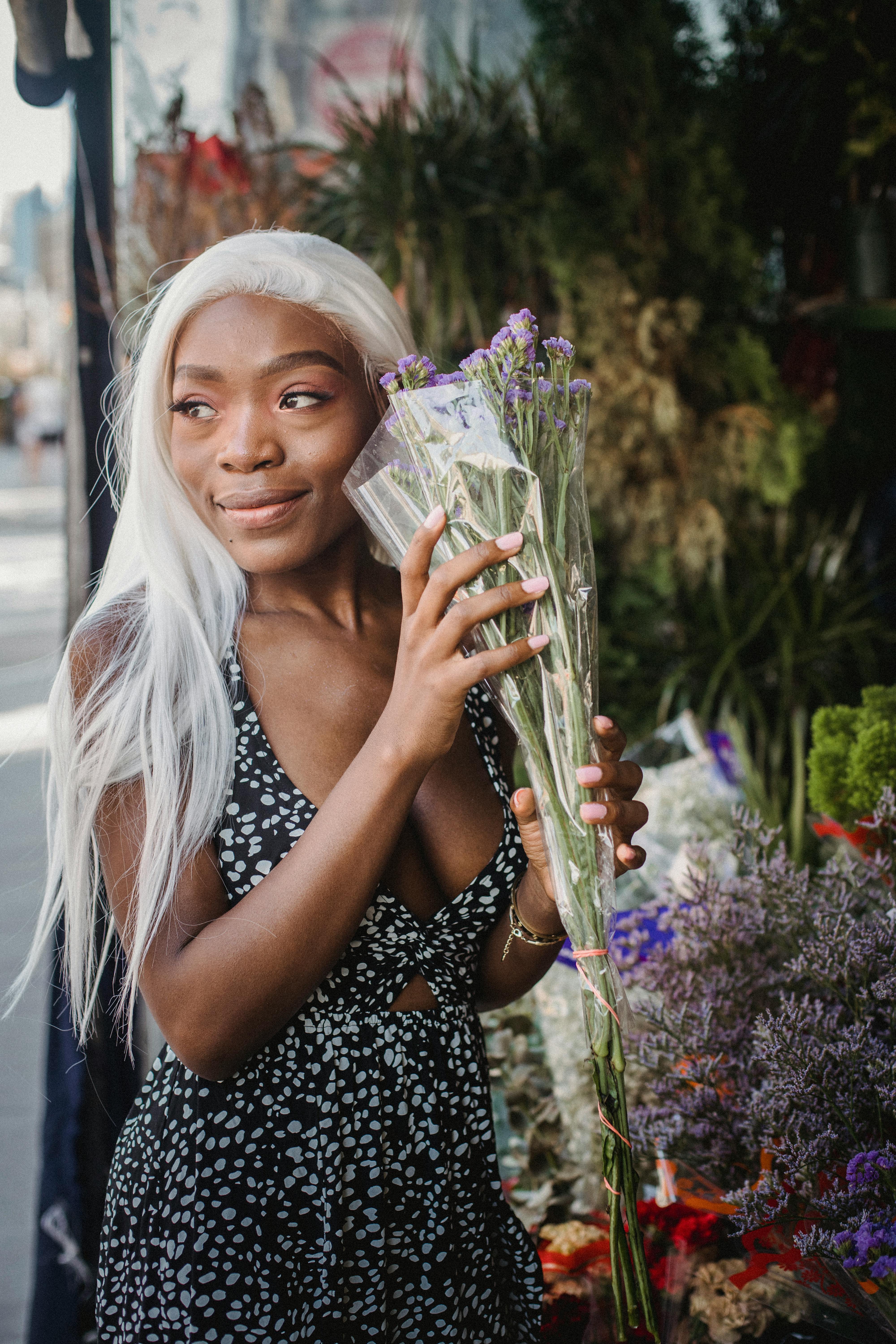 一位高兴的妇女拿着一束花，站在户外花摊前
