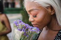 Woman in Purple and White Floral Sleeveless Top Holding Purple Flower Bouquet