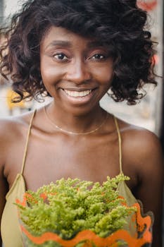 一位快乐的卷发女人，在户外手持一束充满活力的绿色植物，微笑着