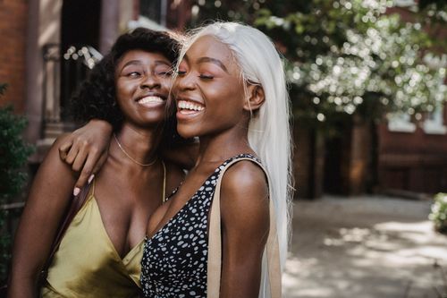 Free Two friends embracing and laughing outdoors, showcasing joyful friendship and happiness. Stock Photo