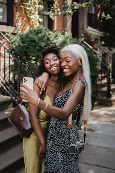 两个朋友在户外阳光明媚地自拍，拥抱微笑