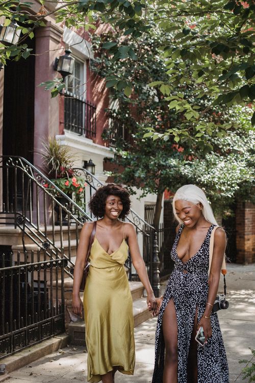 Two friends laughing on a sunny sidewalk, photo by Ketut Subiyanto on Pexels