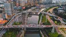 Drone view of large intersection with automobiles in busy city with contemporary skyscrapers and green lawns