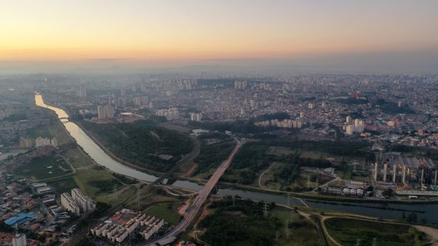 Aerial view of picturesque scenery of long river under bridge and buildings at sundown