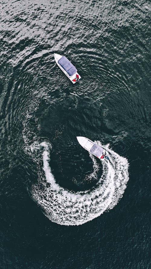 Aerial view of modern motorboat near white yacht on sea surface in daytime