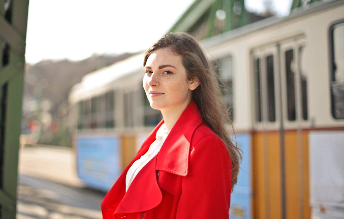 Woman in Red Blazer Standing Near White and Blue Bus