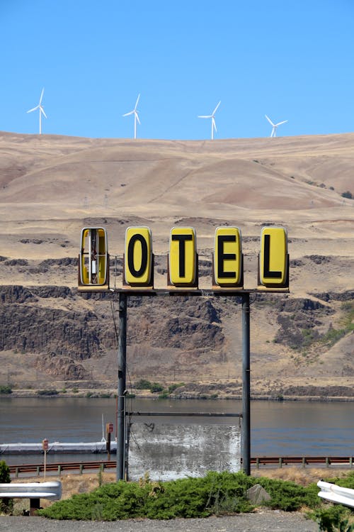 Broken Signage with View of Wind Turbines on Sand Dunes