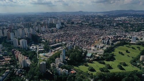 Aerial view of cityscape with densely houses and towers in central district and park in megapolis