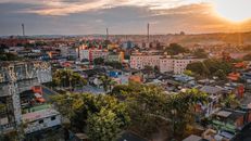 Drone view of country town scenery with low buildings with graffiti and greenery in evening on sundown under cloudy sky