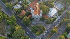 Drone view of contemporary cathedral surrounded by lush trees and located in residential city area on clear summer day