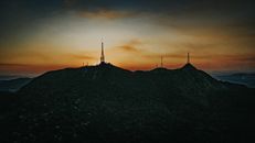 Scenery of spacious hilly terrain with many TV towers under bright sunset sky in countryside