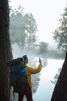徒步旅行者在独自冒险时，捕捉到了河边雾森林的场景