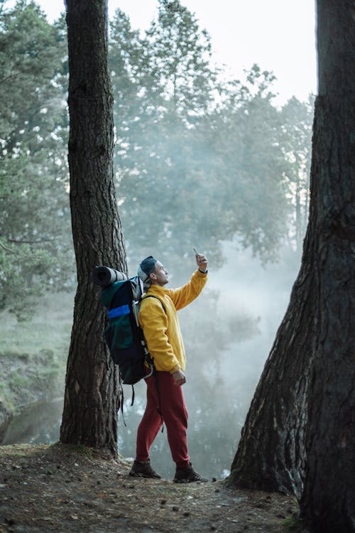 A Man Wearing a Yellow Jacket Holding a Smartphone