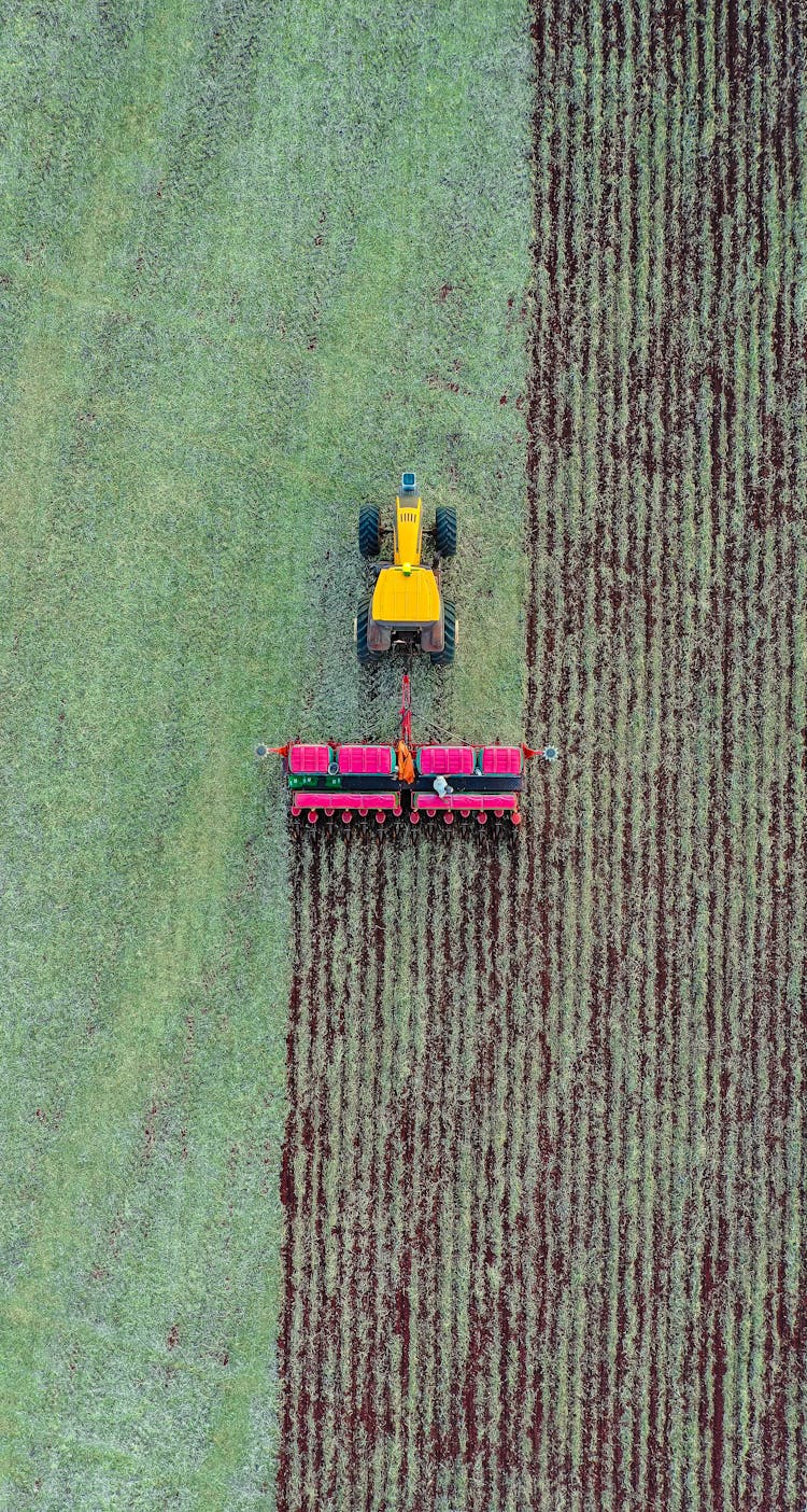 Tractor Plowing Green Field In Daytime