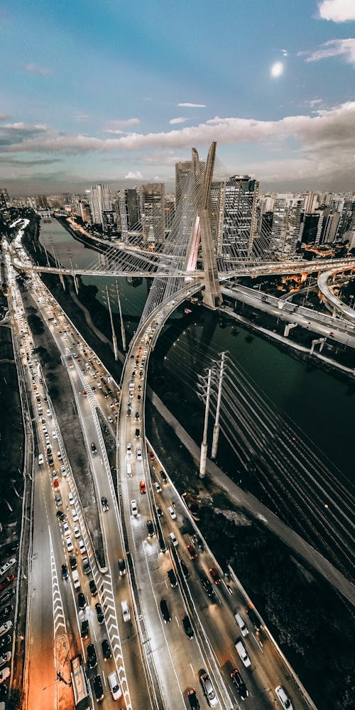 Drone view of transport driving on overpass and Ponte Estaiada bridge over river in Sao Paulo